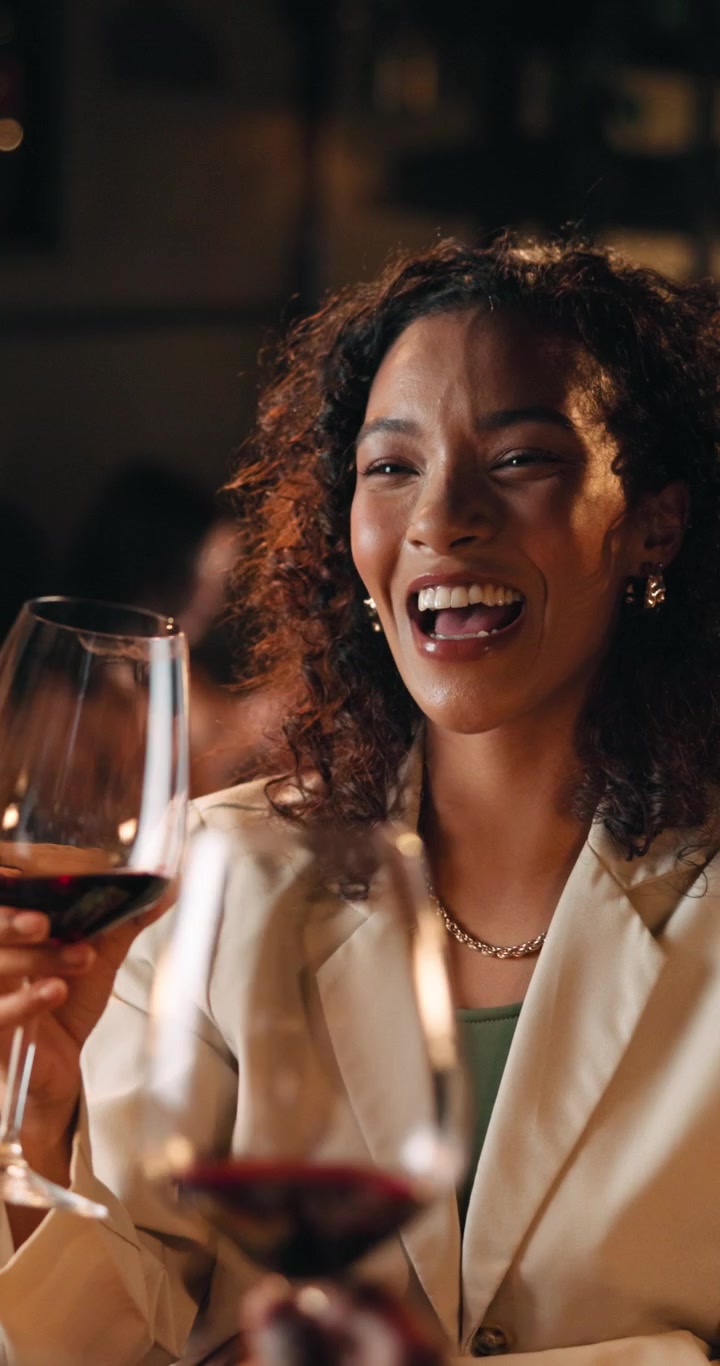 Young Woman Laughing and Drinking Red Wine at a Restaurant
