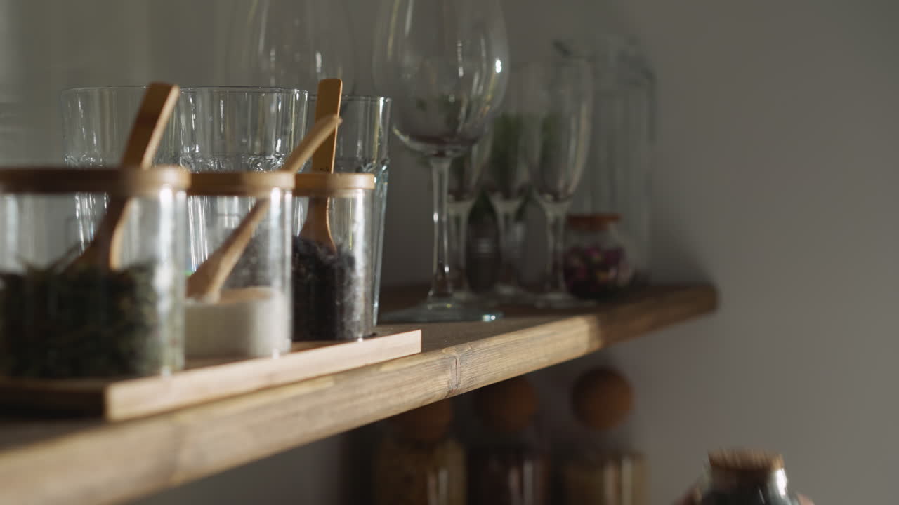 una mujer toma café del armario en el primer plano de la cocina. una mujer alcanza un frasco de vidrio con granos de café en un estante de madera en casa. hacer bebida caliente