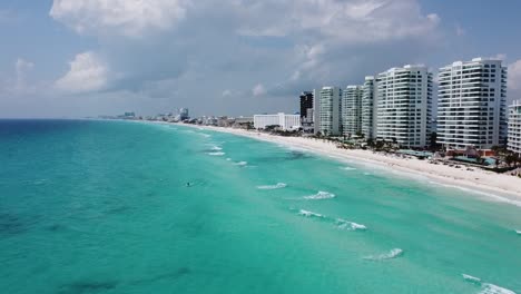 Cancun-shoreline-with-clear-turquoise-water-and-modern-resorts,-aerial-view