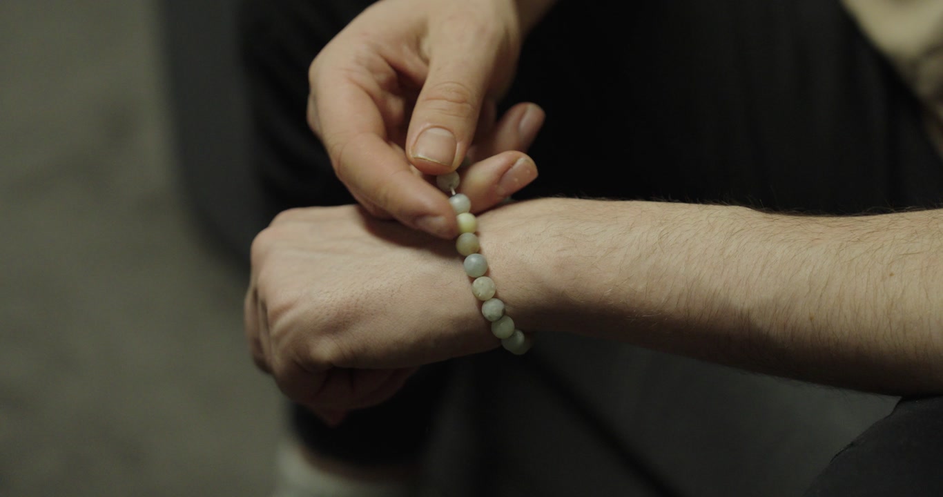 Close-up of hands playing with a bracelet. Concept of nervous habit, fidgeting and casual hand movement.