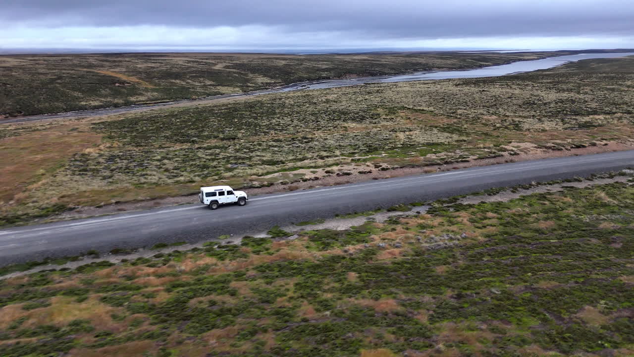 Filmato drone di un veicolo che attraversa un aspro terreno costiero nelle Isole Falkland, ampio filmato aereo rotante.