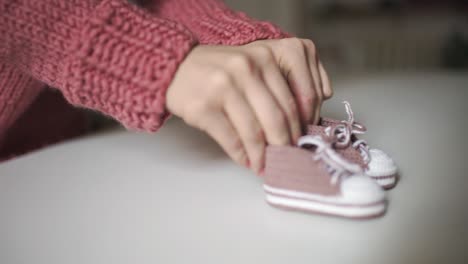 mutterhände spielen mit gestrickten baby-stiefeln. gestrickte kleidung für kinder