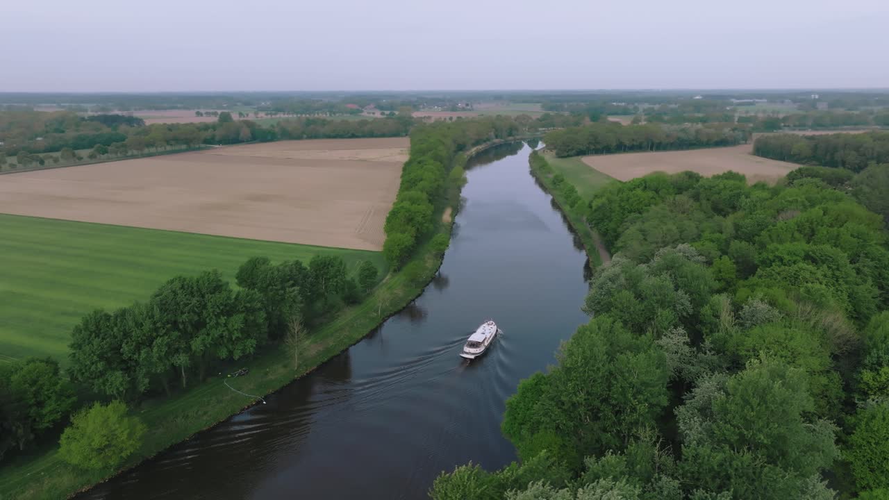 Drone semi orbit showing fertile farmland, green fields and a winding river during spring.