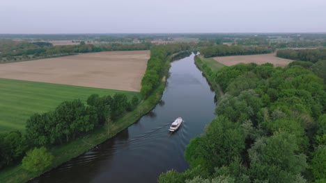 drone semi orbit showing fertile farmland, green fields and a winding river during spring.
