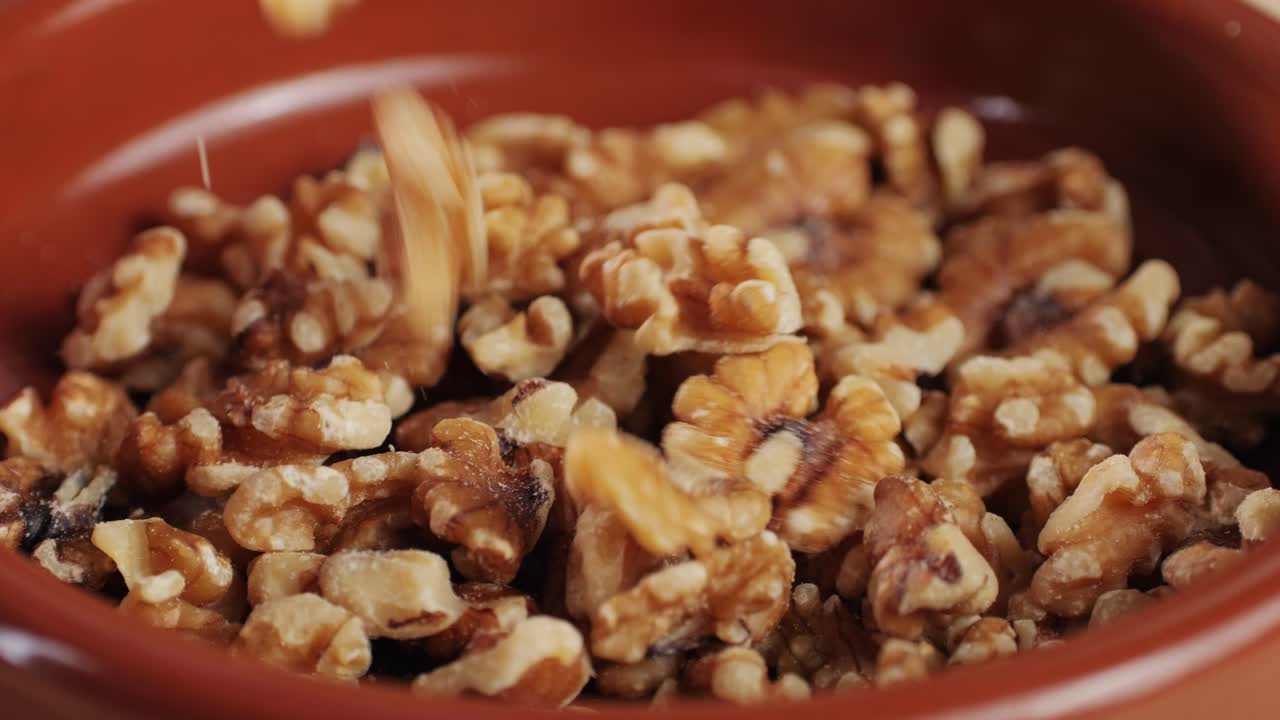 Walnuts without shell falling down on red plate close-up . Peeled nuts. Healthy snacks. Product rich in minerals and vitamins.