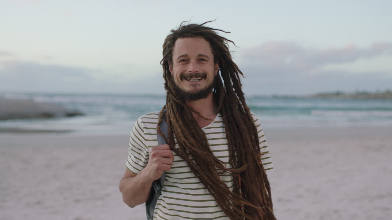 retrato de un hombre joven y confiado con rastas sonriendo alegremente en la playa