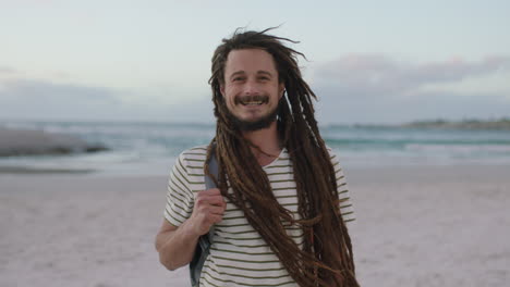 portrait of young confident man with dreadlocks smiling cheerful at beach