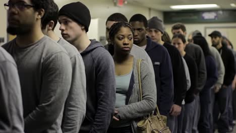 a long line of people waiting in a corridor, highlighting the experience of anticipation in a shared moment of quiet reflection and community engagement