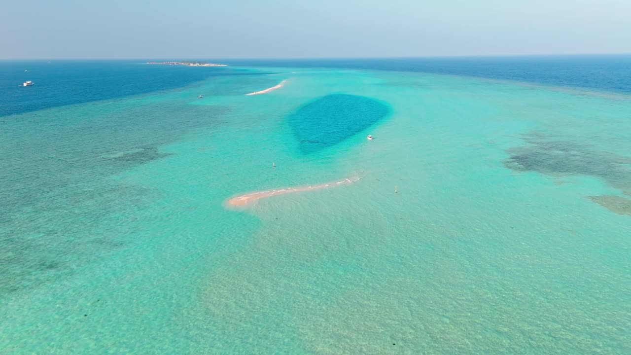 An awe-inspiring aerial drone view captures the Rasdhoo Sandbanks glowing under the soft, golden light of sunset in the Maldives.