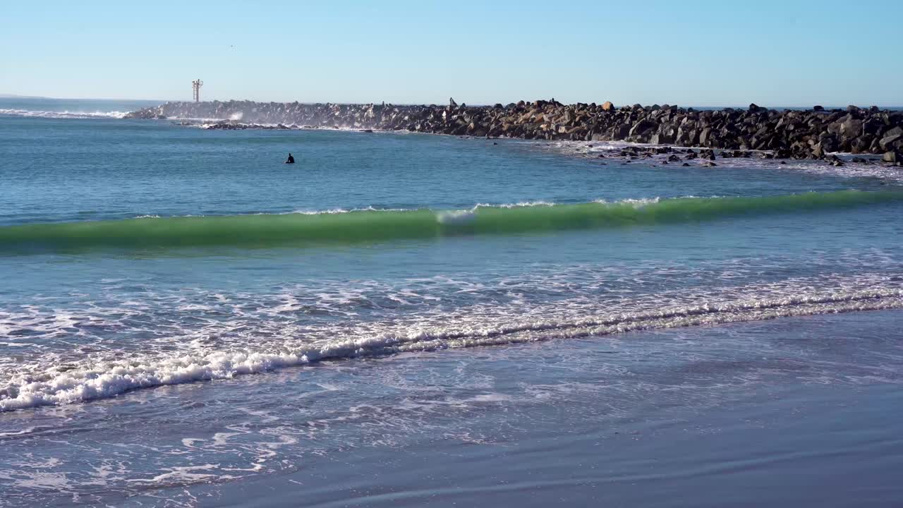 surfista en el mar con olas extremas rompiendo en un muro de ruptura rocoso