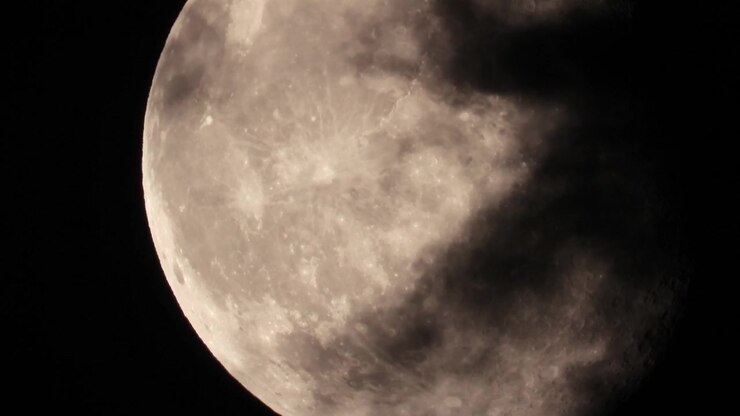 Vista cativante da lua cheia com nuvens a flutuar pelo céu noturno, criando uma cena misteriosa e atmosférica