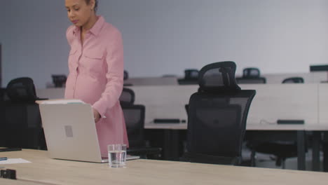 Tired-Pregnant-Woman-Sitting-At-Desk-In-The-Office