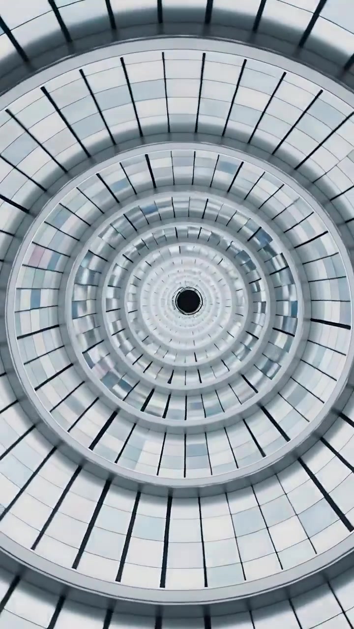 Video verticale: Telecamera che zooma verso l'interno attraverso anelli concentrici verso un'apertura centrale, rivelando pannelli.