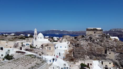 Imágenes-Aéreas-De-Oia,-Las-Famosas-Casas-Blancas-De-Santorini-Y-Cúpulas-Azules-En-El-Borde-Del-Acantilado-Y-La-Laguna-Azul