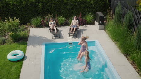 a group of young people relax by the pool, mother and daughter jump into the water