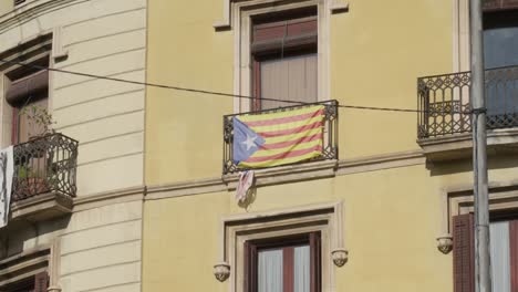 catalonia flag raised on building balcony in barcelona city, handheld