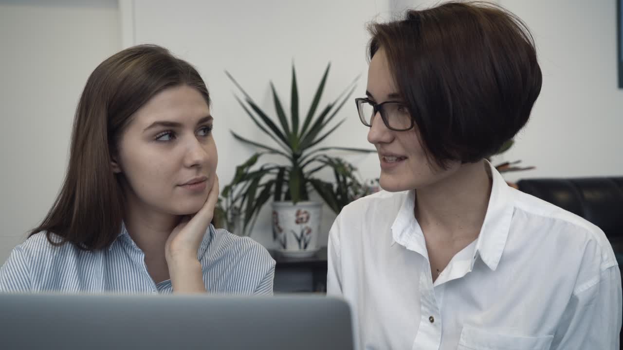 dos mujeres discutiendo en la computadora portátil en la oficina