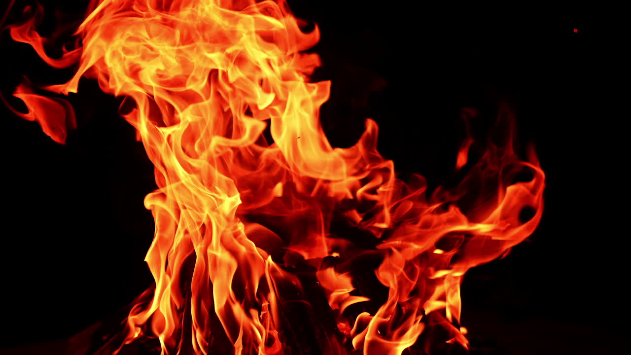 Wooden logs in a stack burning well in the campfire. Isolated bonfire at black background. Close up.