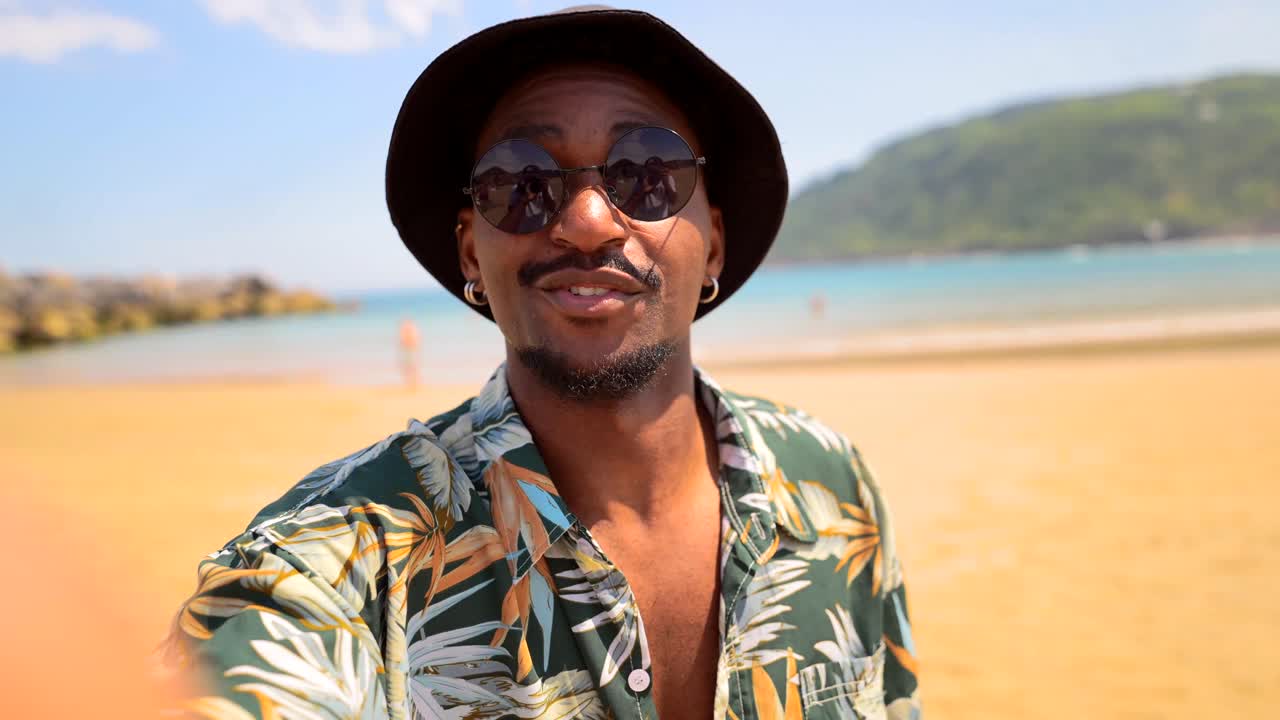 Mand på stranden med solbriller og hat