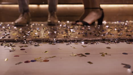 Camera-Focuses-On-The-Wooden-Floor-Full-Of-Confetti-And-Man-Shoes-And-Woman-Heels-Moving-While-They-Dance