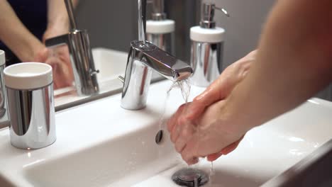 close-up of person disinfecting hands with tab water in clean bathroom