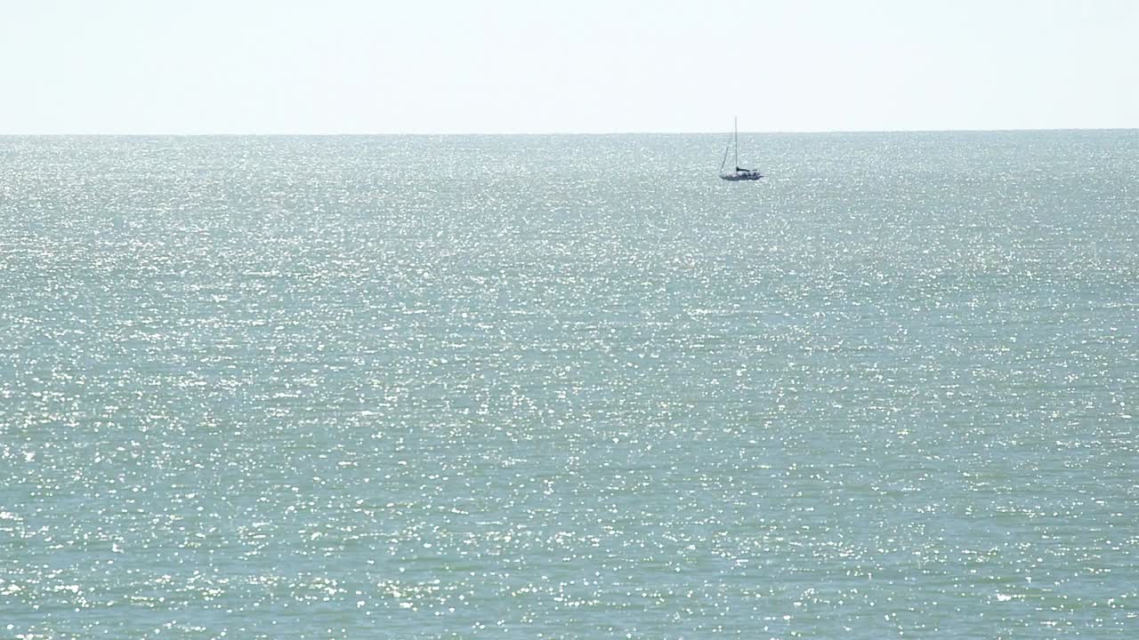 멀리 작은 범선과 단색 바다의 넓은 샷