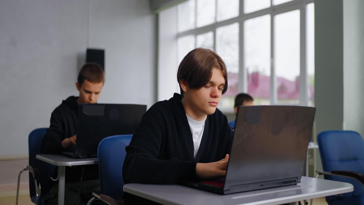 estudiantes trabajando en computadoras portátiles en un aula