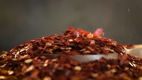 flakes of red hot chili pepper in wooden spoon closeup on a kitchen table.