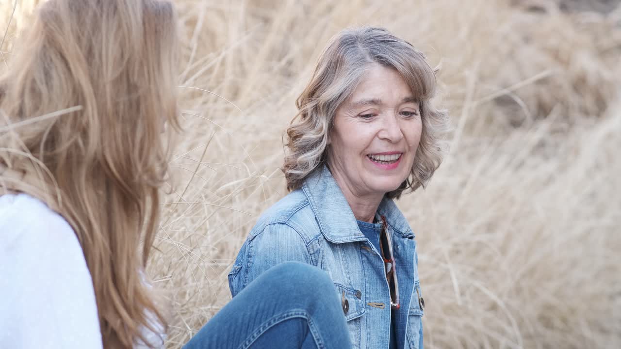 Two mature woman chatting relaxed outdoors