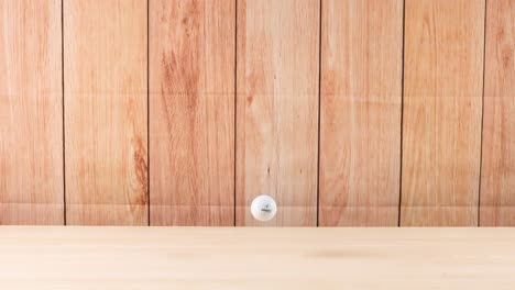 a golf ball rolls across a wooden floor