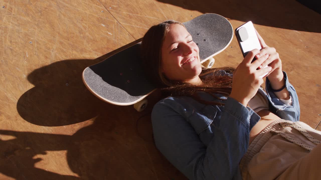 Video di felice skater donna caucasica che riposa e usa lo smartphone