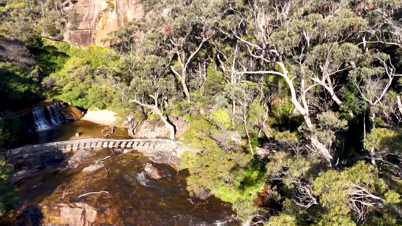 Filmagem de drone percorrendo uma cachoeira e uma densa floresta de eucaliptos em Wentworth Falls, Austrália
