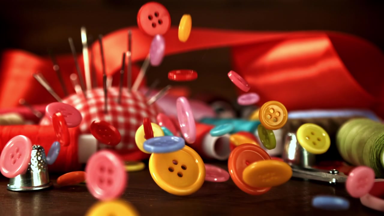 Bunte Knöpfe fallen in Zeitlupe auf Nähzubehör