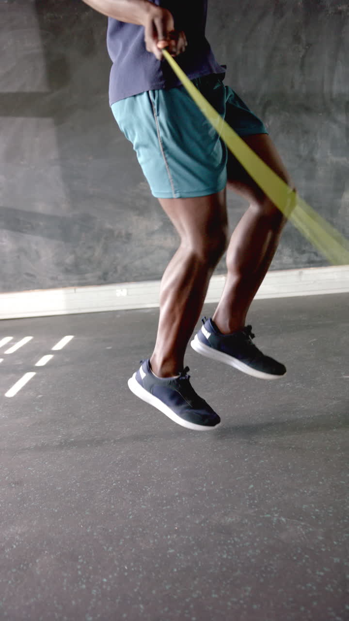 Vertical video: Jumping rope in gym, athletic man exercising with focus and determination