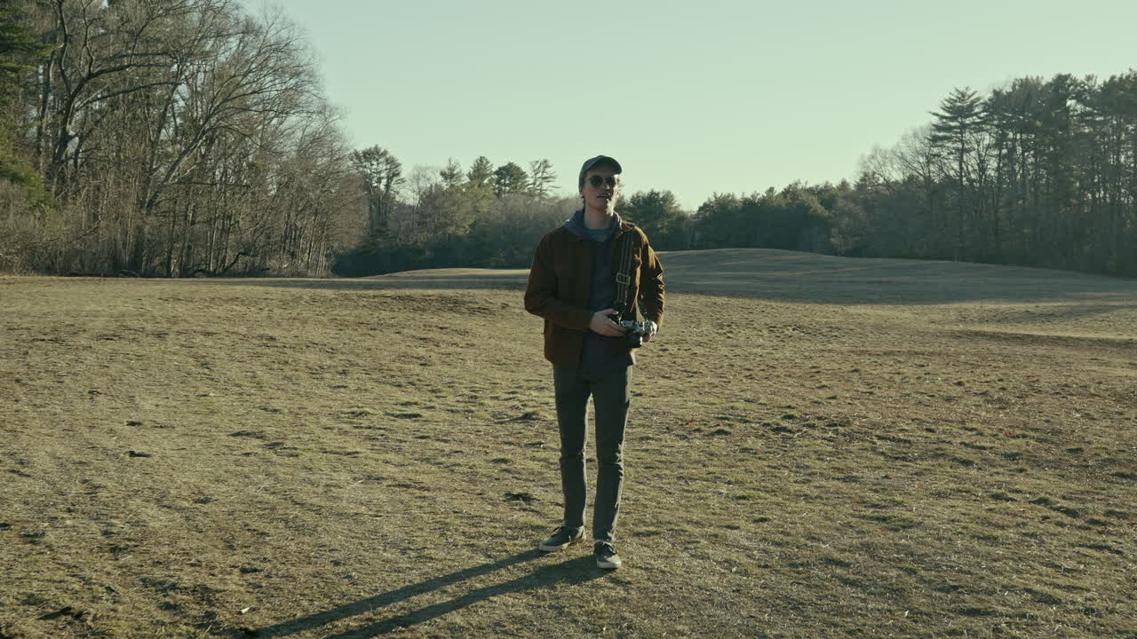 Young photographer raises camera to take a photograph of the woods