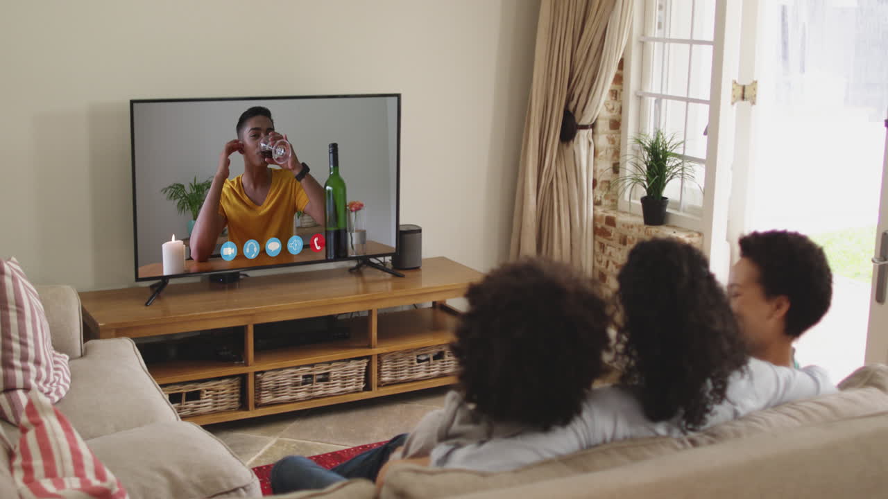 Famiglia afroamericana che fa una videochiamata in TV mentre è seduta sul divano a casa