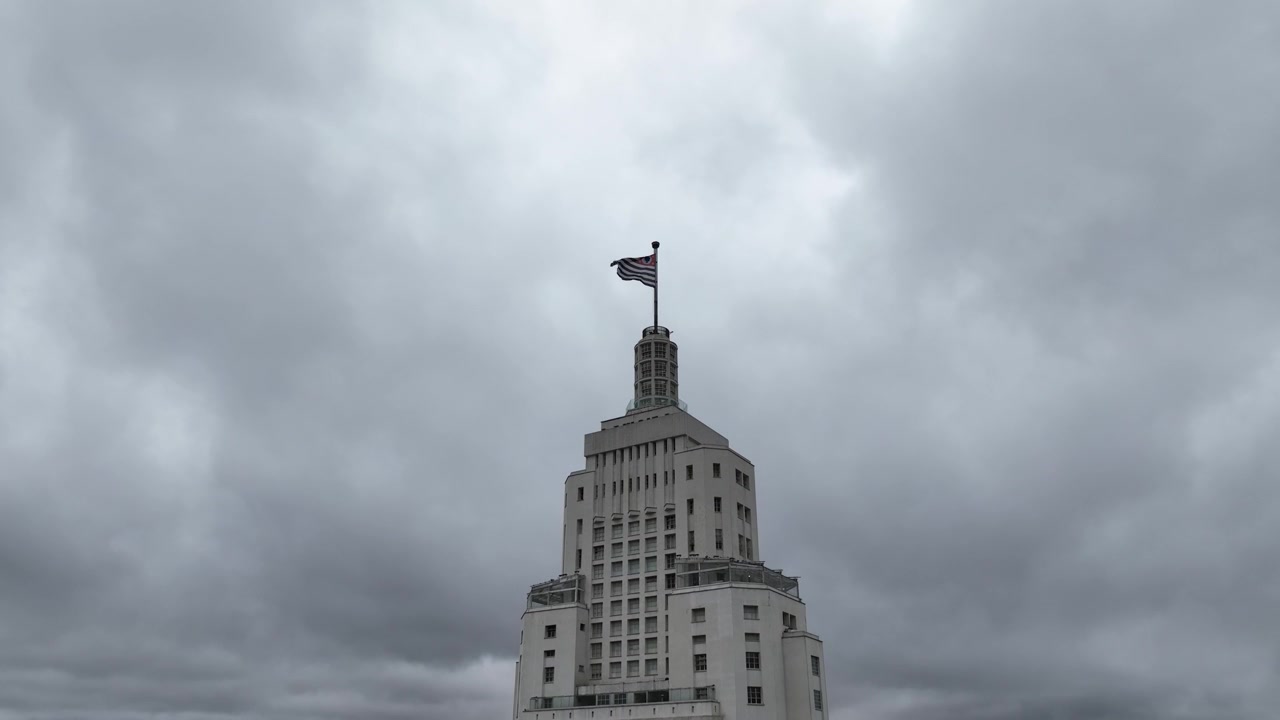 Drone descending over the Sao Paulo state flag on top of Farol Santander building in downtown Sao Paulo Brazil