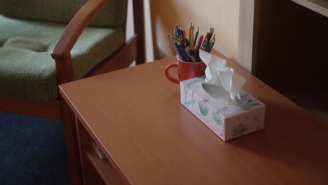 pañuelos de papel y lápices de color en una mesa alrededor de la cual hay sillas