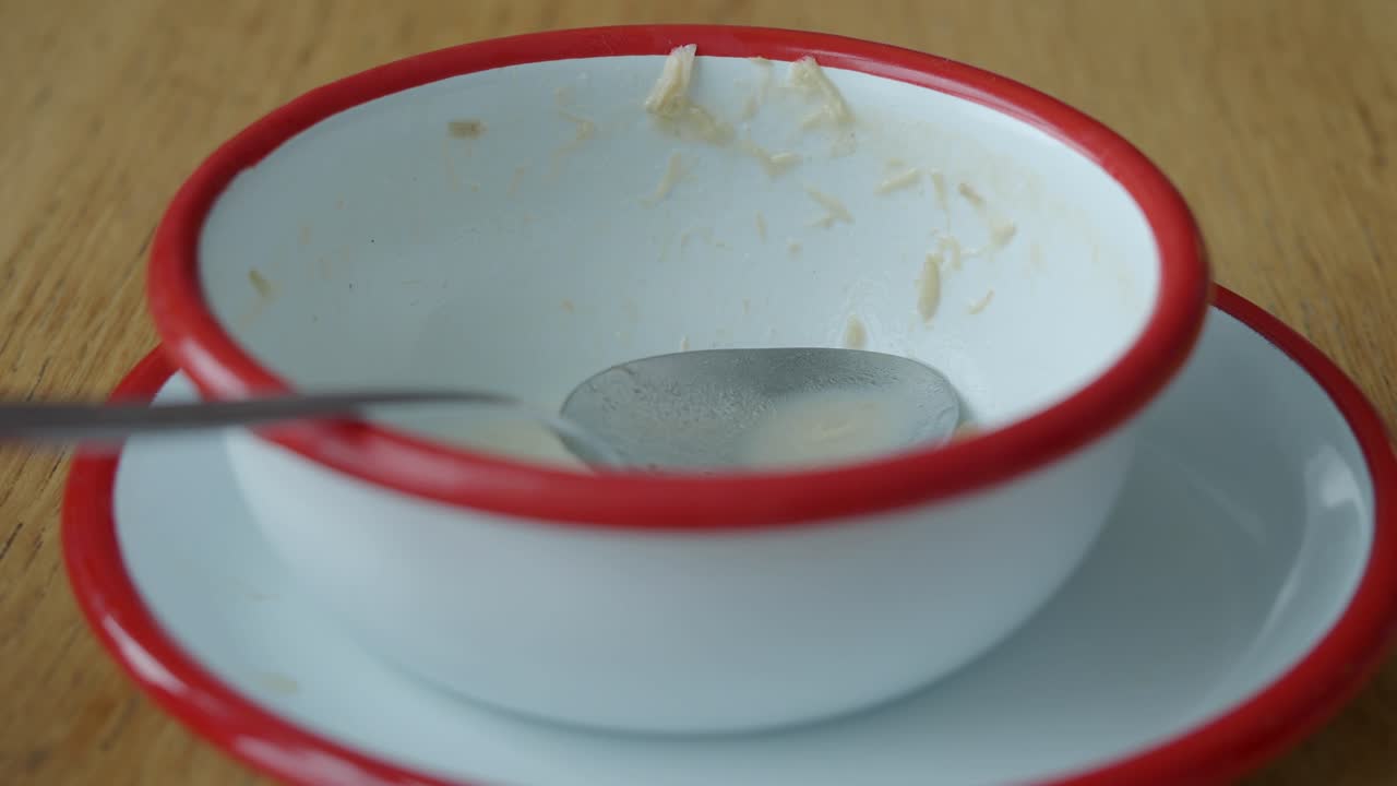 Leere Schüssel mit Löffel und Essensresten auf Holztisch