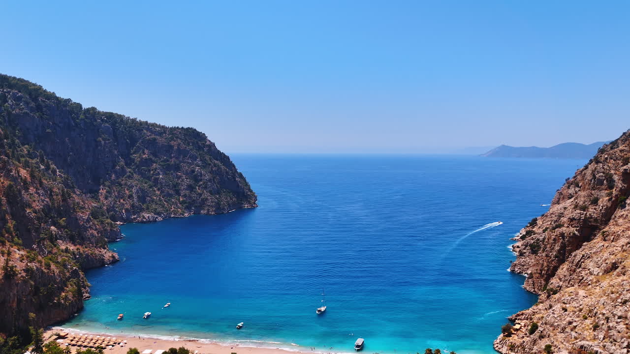 Serene coastal view of a hidden bay. Bright blue waters meet rugged cliffs in a tranquil bay, inviting visitors to explore the secluded beach and nature