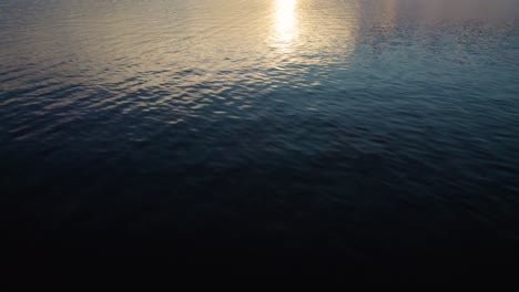 Cinematic-drone-tilt-up-dolly-shot-of-a-lake-and-mountains-with-sunset