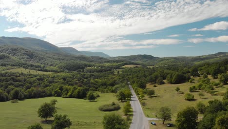 aerial drone shot over extra-urban road in forest valley, country scene