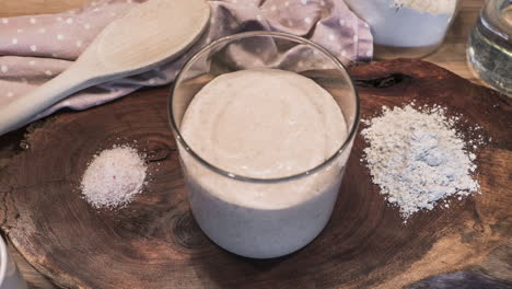 sourdough starter fermentation process - flour and water mixture rising in a glass jar - timelapse, zoom-out