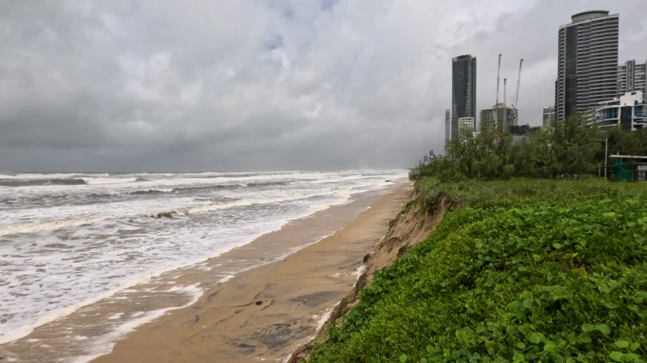 호주 골드코스트 근처의 폭풍우가 몰아치는 해안 해변은 거센 파도와 구름이 가득한 하늘과 함께 해안 침식 현상을 보여줍니다.