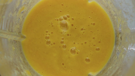 Top-view-yellow-smoothie-splashing-in-blender-super-slow-motion-closeup.