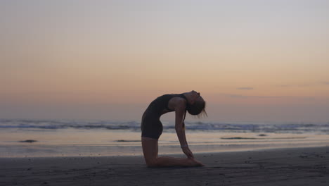 woman practicing yoga at sunrise on the beach
