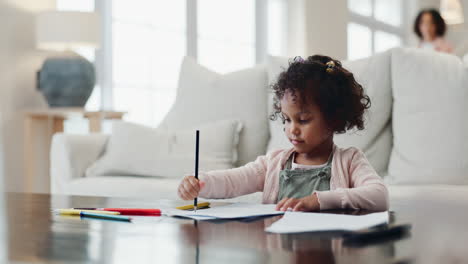 young girl sitting at a table coloring with a pencil