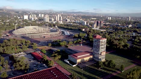 toma aerea de la rectoria de la unam, detras del estadio universitario y de fondo el occidente del sur de la ciudad de mexico en horas de la madrugada