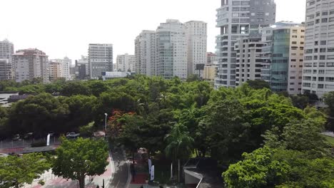 drone flying over santo domingo iberoamerican park with views of tall buildings in the background, upper middle class residential area