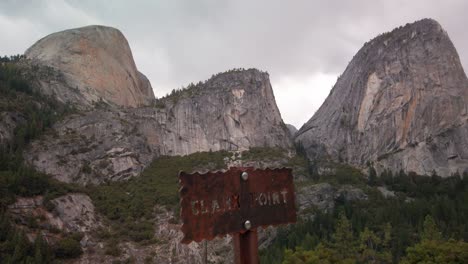 tilting up shot to reveal hiking trailhead sign with the backside of half dome in the background